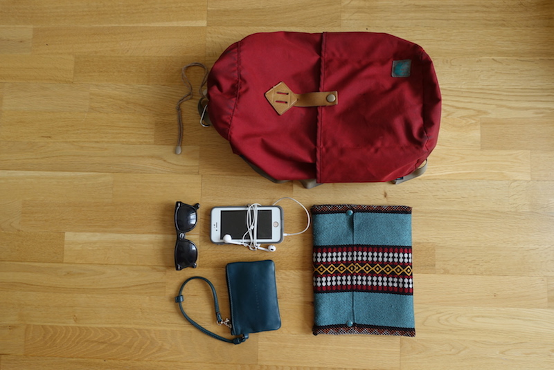 Small flat purse, phone, sunglasses and day bag packed in device compartment