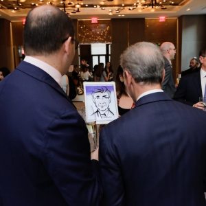 A Drawing Booth artist showing clients their portraits